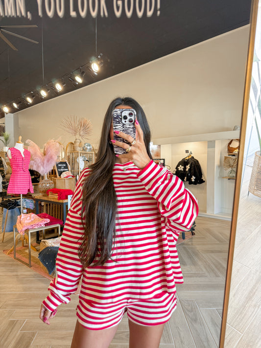 Person wearing a red and white striped outfit taking a mirror selfie in a store.
